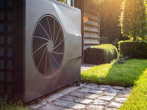 Engineer inspecting an air source heat pump outside a modern home