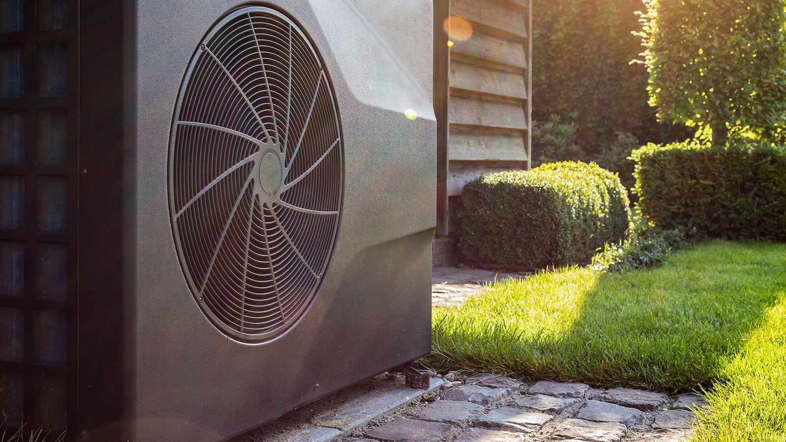 Engineer inspecting an air source heat pump outside a modern home