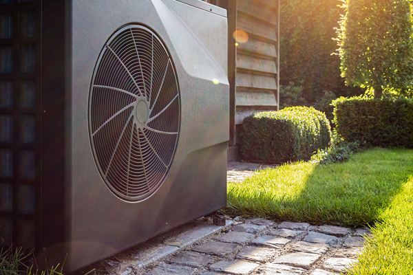 Engineer inspecting an air source heat pump outside a modern home